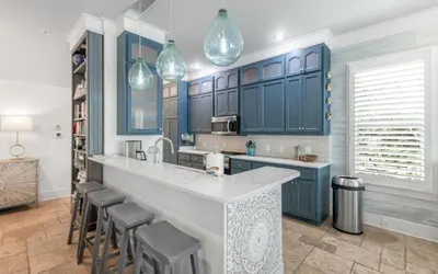 a kitchen with blue cabinets and bar stools at SeaGroovInn by Oversee 30A in Santa Rosa Beach