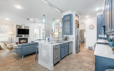a kitchen with blue cabinets and a living room at SeaGroovInn by Oversee 30A in Santa Rosa Beach