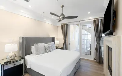 a white bedroom with a bed and a tv at Serenity by Oversee 30A in Rosemary Beach