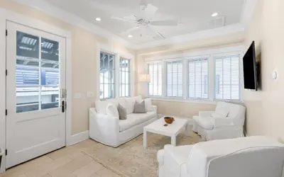 a living room with white furniture and a tv at Serenity by Oversee 30A in Rosemary Beach
