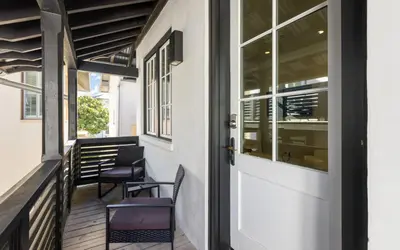 a porch with two chairs and a door at Serenity by Oversee 30A in Rosemary Beach