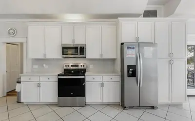 a kitchen with white cabinets and a refrigerator at Shores Fun by Oversee 30A in Seacrest