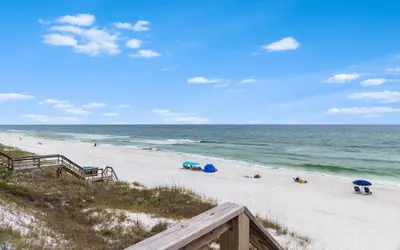a beach with people laying on the sand and the ocean at Shores Fun by Oversee 30A in Seacrest