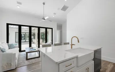 a white kitchen with a sink and a living room at Slim Shady by Oversee 30A in Santa Rosa Beach