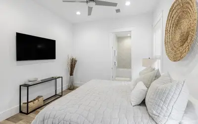 a white bedroom with a bed and a flat screen tv at Slim Shady by Oversee 30A in Santa Rosa Beach