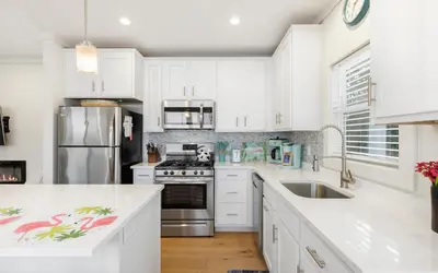 a kitchen with white cabinets and a stainless steel refrigerator at Sun Palace by Oversee 30A in Santa Rosa Beach