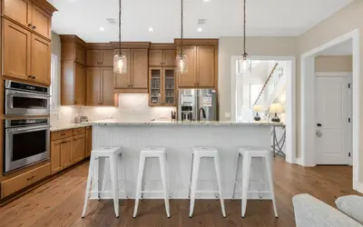 a kitchen with wooden cabinets and a island with bar stools at Sunseeker by Oversee 30A in Santa Rosa Beach