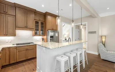 a kitchen with wooden cabinets and a island with bar stools at Sunseeker by Oversee 30A in Santa Rosa Beach