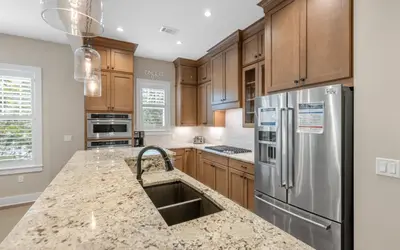 a kitchen with wooden cabinets and a stainless steel refrigerator at Sunseeker by Oversee 30A in Santa Rosa Beach