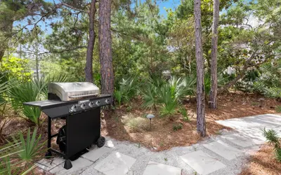 a grill in the middle of a garden with trees at Sunseeker by Oversee 30A in Santa Rosa Beach