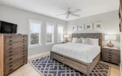 a bedroom with a bed and a tv and windows at Sunset Beach Villa A101 by Oversee 30A in Rosemary Beach