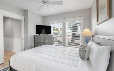 a white bedroom with a large bed and a television at Sunset Beach Villa A101 by Oversee 30A in Rosemary Beach