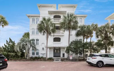 a white building with palm trees in front of it at Sunset Beach Villa A101 by Oversee 30A in Rosemary Beach