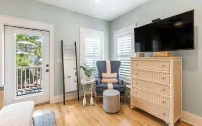 a bedroom with a tv and a chair and a dresser at Surfing Cowboy by Oversee 30A in Santa Rosa Beach