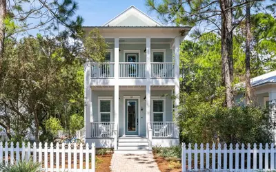 a white picket fence in front of a white house at Surfing Cowboy by Oversee 30A in Santa Rosa Beach