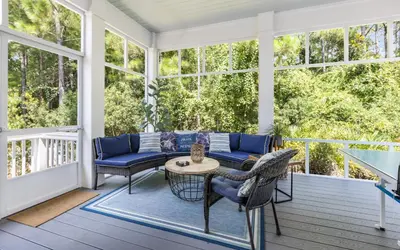 a screened porch with a couch and a table and chairs at Surfing Cowboy by Oversee 30A in Santa Rosa Beach