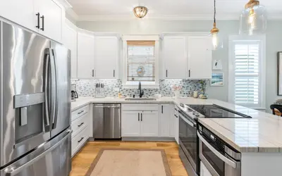 a kitchen with white cabinets and a stainless steel refrigerator at Surfing Cowboy by Oversee 30A in Santa Rosa Beach