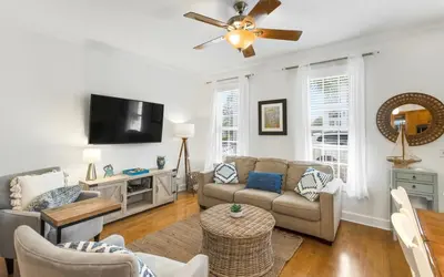 a living room with a couch and a flat screen tv at The Fab Crab by Oversee 30A in Seacrest