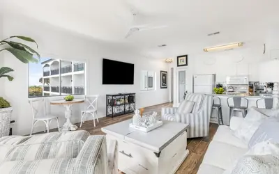 a living room with white furniture and a kitchen at The Palms by Oversee 30A in Santa Rosa Beach