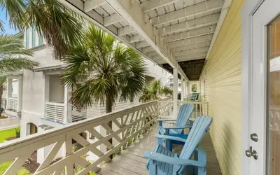 two blue chairs on a porch with palm trees at Tucked-Away at Inlet Beach by Oversee 30A in Inlet Beach