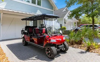 a red golf cart parked in front of a house at Two Rocking Chairs on a Porch by Oversee 30A in Watersound Beach