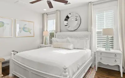 a white bedroom with a bed and a clock on the wall at Two Rocking Chairs on a Porch by Oversee 30A in Watersound Beach