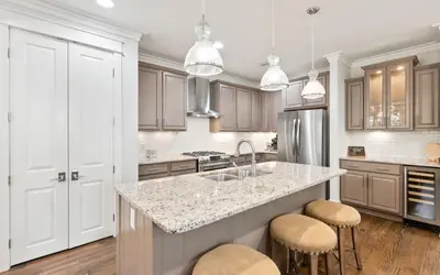 a kitchen with a sink and a counter with stools at Two Rocking Chairs on a Porch by Oversee 30A in Watersound Beach