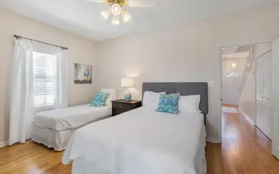 a white bedroom with two beds and a window at Villa Del Lago by Oversee 30A in Seacrest