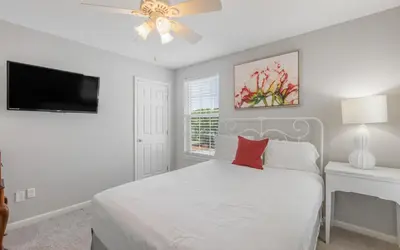 a white bedroom with a bed and a ceiling fan at Villa Del Lago by Oversee 30A in Seacrest