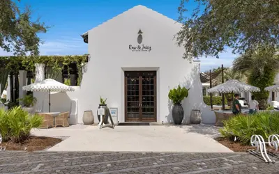 a white building with a door and chairs and umbrellas at Villa Del Lago by Oversee 30A in Seacrest