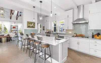 a kitchen with white cabinets and a bar with stools at Winters End by Oversee 30A in Santa Rosa Beach