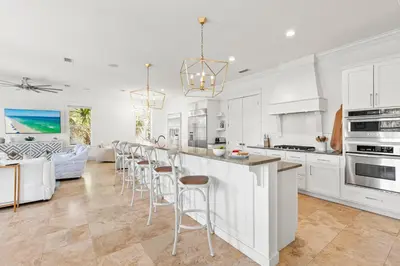 a kitchen with white cabinets and a bar with stools at Steps to Beach, Large Private Pool, Bikes, Luxury in Santa Rosa Beach