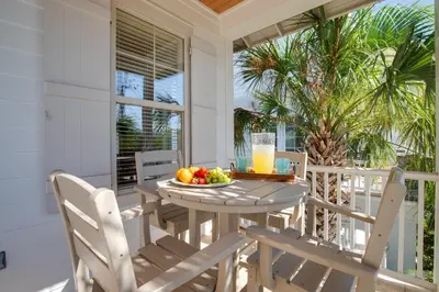 a table and chairs on a porch with a bowl of fruit at Steps to Beach, Large Private Pool, Bikes, Luxury in Santa Rosa Beach