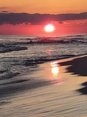 a sunset on the beach with the sun setting at 3 Bdrm Condo- 4 pools, hot tub & walk to Beach in Panama City Beach
