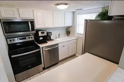 a kitchen with white cabinets and a black appliances at 3 Bdrm Condo- 4 pools, hot tub & walk to Beach in Panama City Beach