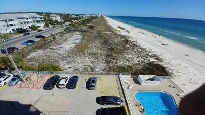 an aerial view of a beach with cars parked in a parking lot at ON THE BEACH! COUPLES GETAWAY,HONEYMOON SWEET, Perfectly Cozy Beach Front Condo, full kitchen, pool, free parking,CHECK-IN AT DOOR in Panama City Beach