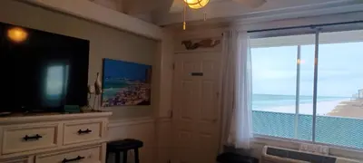 a room with a television and a window with a view of the beach at ON THE BEACH! COUPLES GETAWAY,HONEYMOON SWEET, Perfectly Cozy Beach Front Condo, full kitchen, pool, free parking,CHECK-IN AT DOOR in Panama City Beach