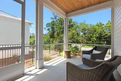 a screened in porch with two chairs and a table at Wendell's Place in Inlet Beach