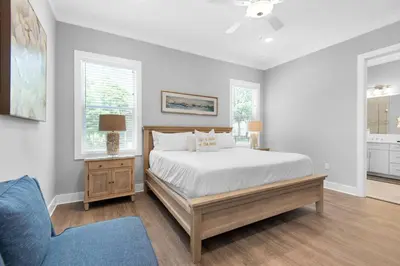 a bedroom with a bed and a chair and windows at Wendell's Place in Inlet Beach