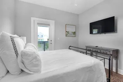 a white bedroom with a bed and a television at Wendell's Place in Inlet Beach
