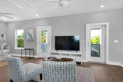 a living room with a flat screen tv and two chairs at Wendell's Place in Inlet Beach