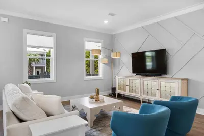 a living room with a tv and blue chairs at Ocean Pearl in Inlet Beach
