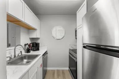 a kitchen with a sink and a stainless steel refrigerator at Sand Castle West #G6 in Panama City Beach