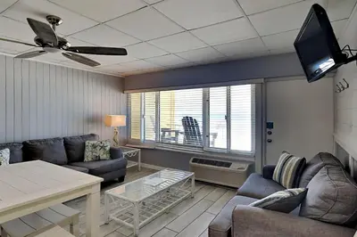 a living room with a couch and a table and a tv at Continental #221 in Panama City Beach