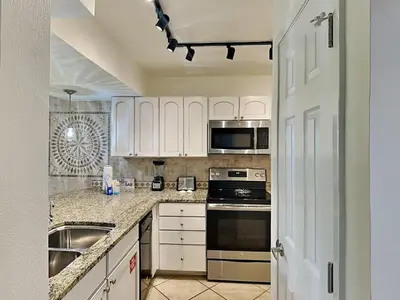 a kitchen with white cabinets and stainless steel appliances at Edgewater Villa #2008 Gulf Breeze Getaway in Panama City Beach