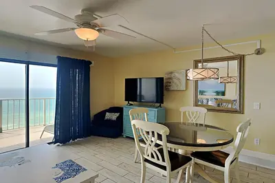 a living room with a dining room table and a tv at Summit Beach Resort #1202 in Panama City Beach
