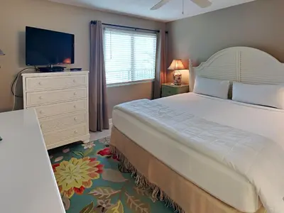 a bedroom with a large bed and a flat screen tv at Mariner East #306 in Panama City Beach