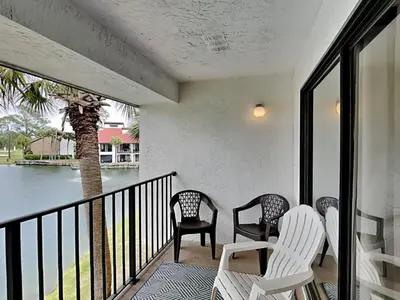 a porch with three chairs and a palm tree at Edgewater Villa #909 in Panama City Beach