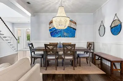 a dining room with a table and chairs and a chandelier at Gone Coastal in Santa Rosa Beach