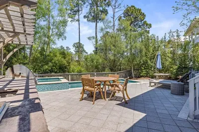 a patio with a table and chairs next to a pool at Gone Coastal in Santa Rosa Beach
